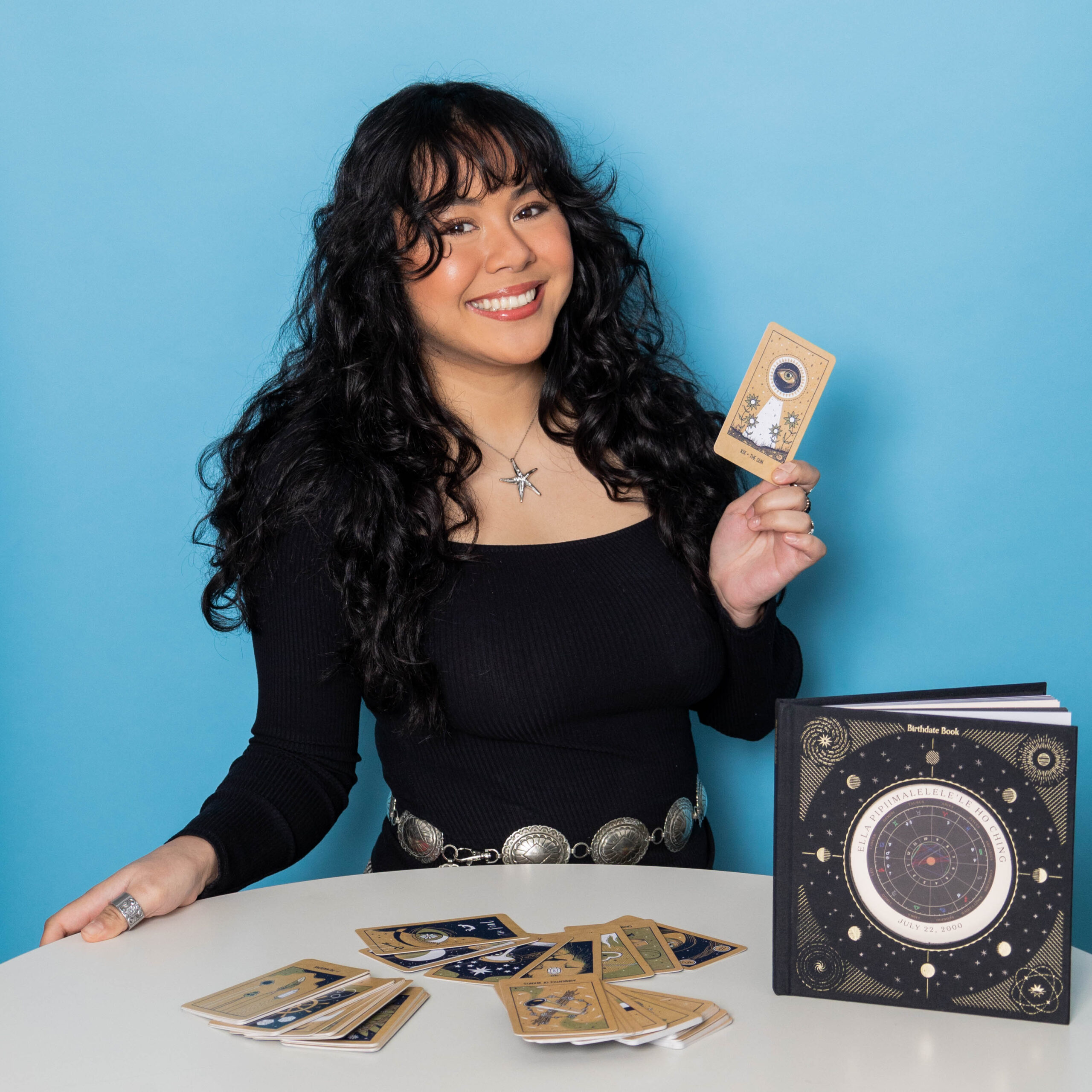 Headshot of a woman in a black color shirt holding tarot cards