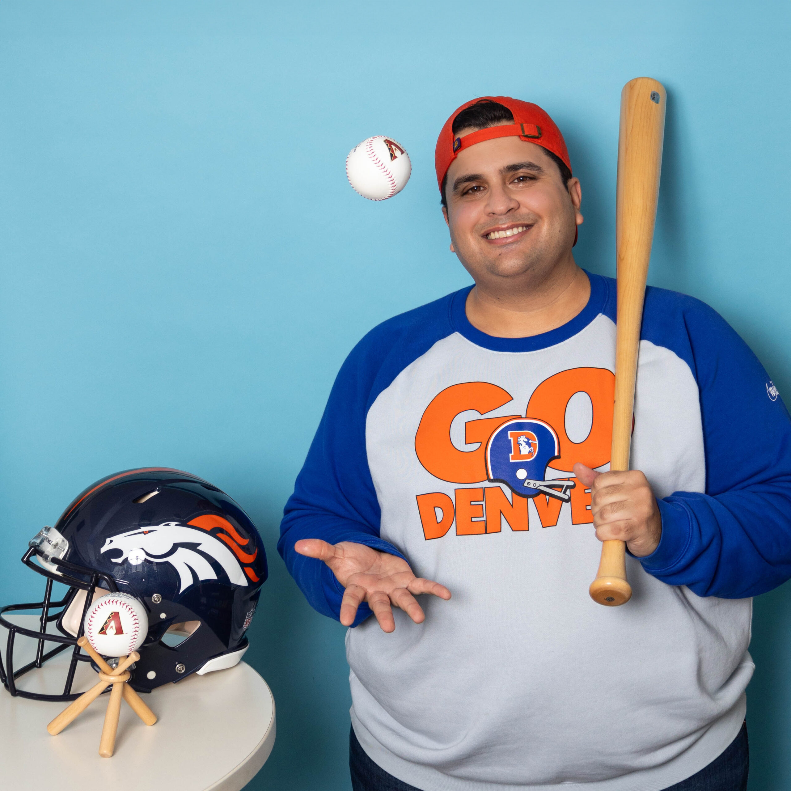 Headshot of a man in a baseball shirt and holding sports equipment