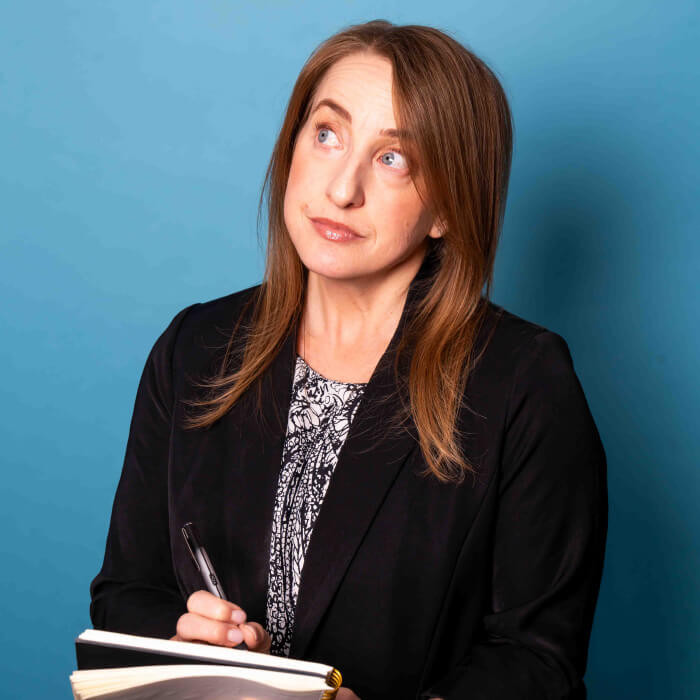 Headshot of a women in a black blazer writing in a book | Janelle Brannock