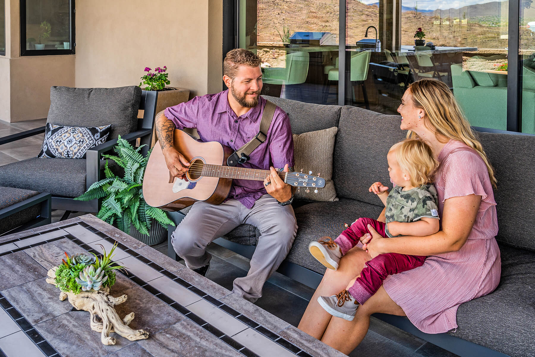 Family sitting on a outdoor couch, Man playing the guitar