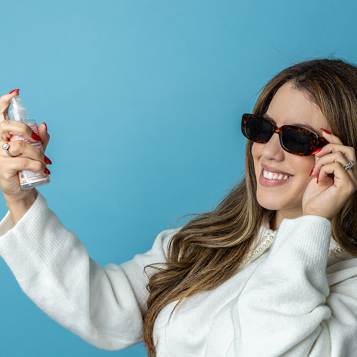 Headshot of women wearing sunglasses and holding a spray bottle