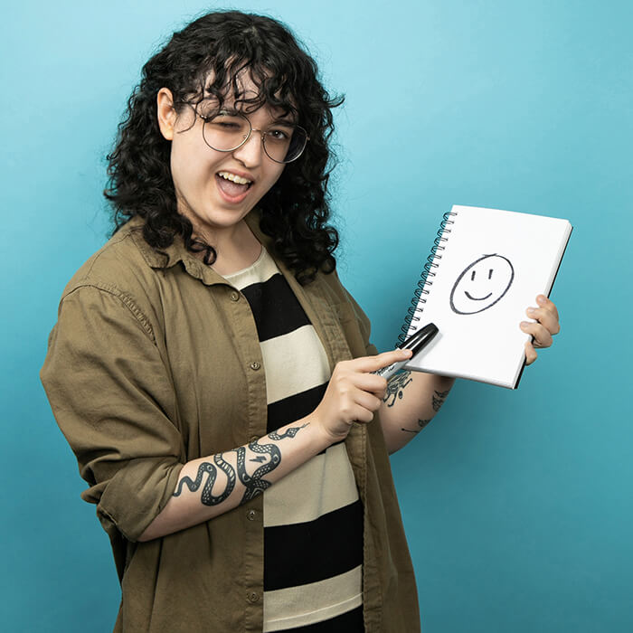 A women holding a note pad with a smiley face | Alyssa Clayton