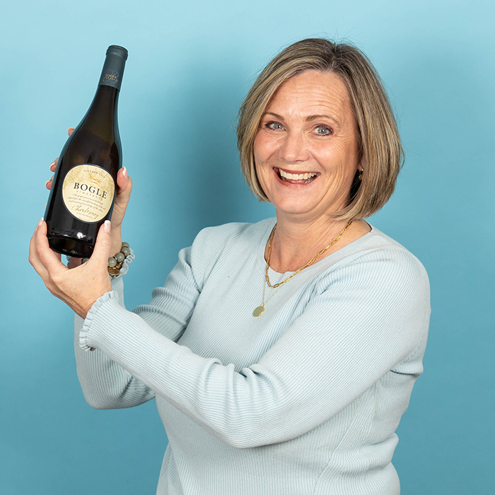 Headshot of a women in a light blue top holding a bottle of wine | Connie Waters