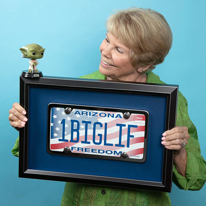 Women headshot of her holding a framed license plate