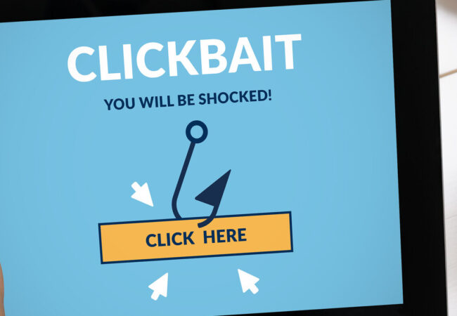 Hand holding a tablet with clickbait concept on screen.