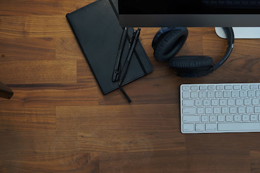 Desk top with keyboard, notebook, computer monitor, and headphones